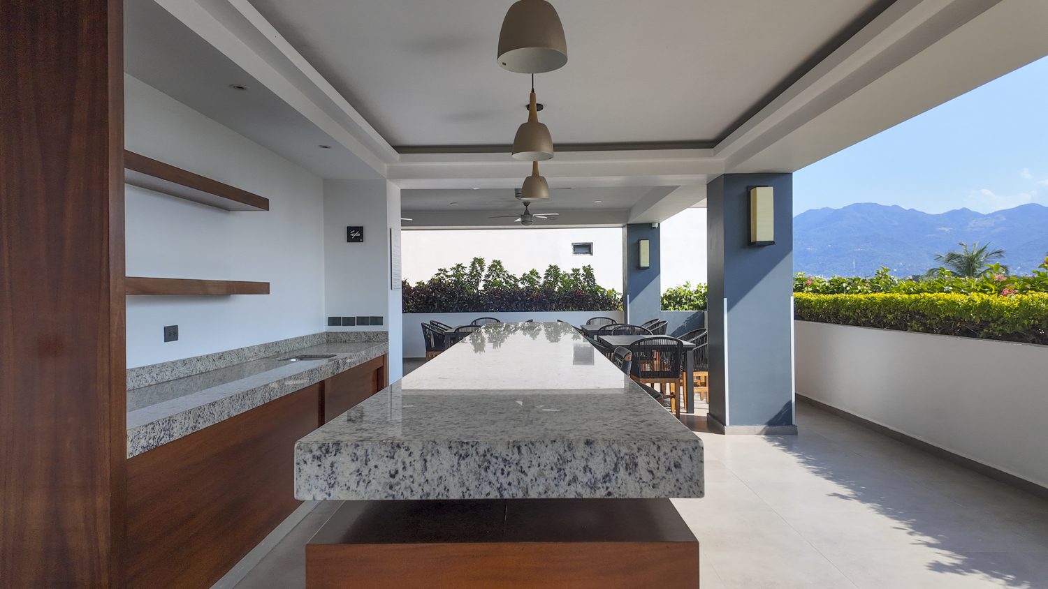 Rooftop BBQ and bar terrace with granite island and mountain views at Zoho Skies